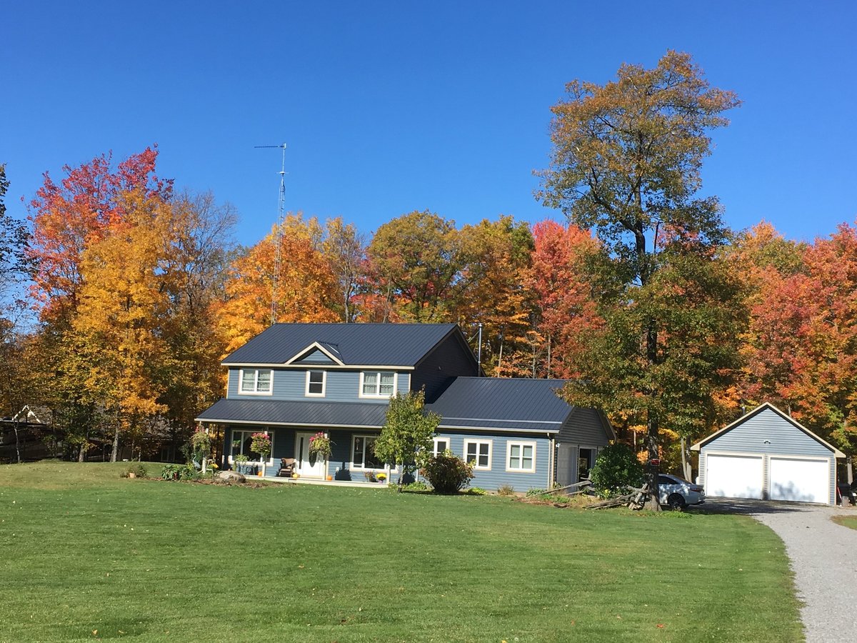 Mid-distance view of a two storey blue house in the country in bright autumn sun