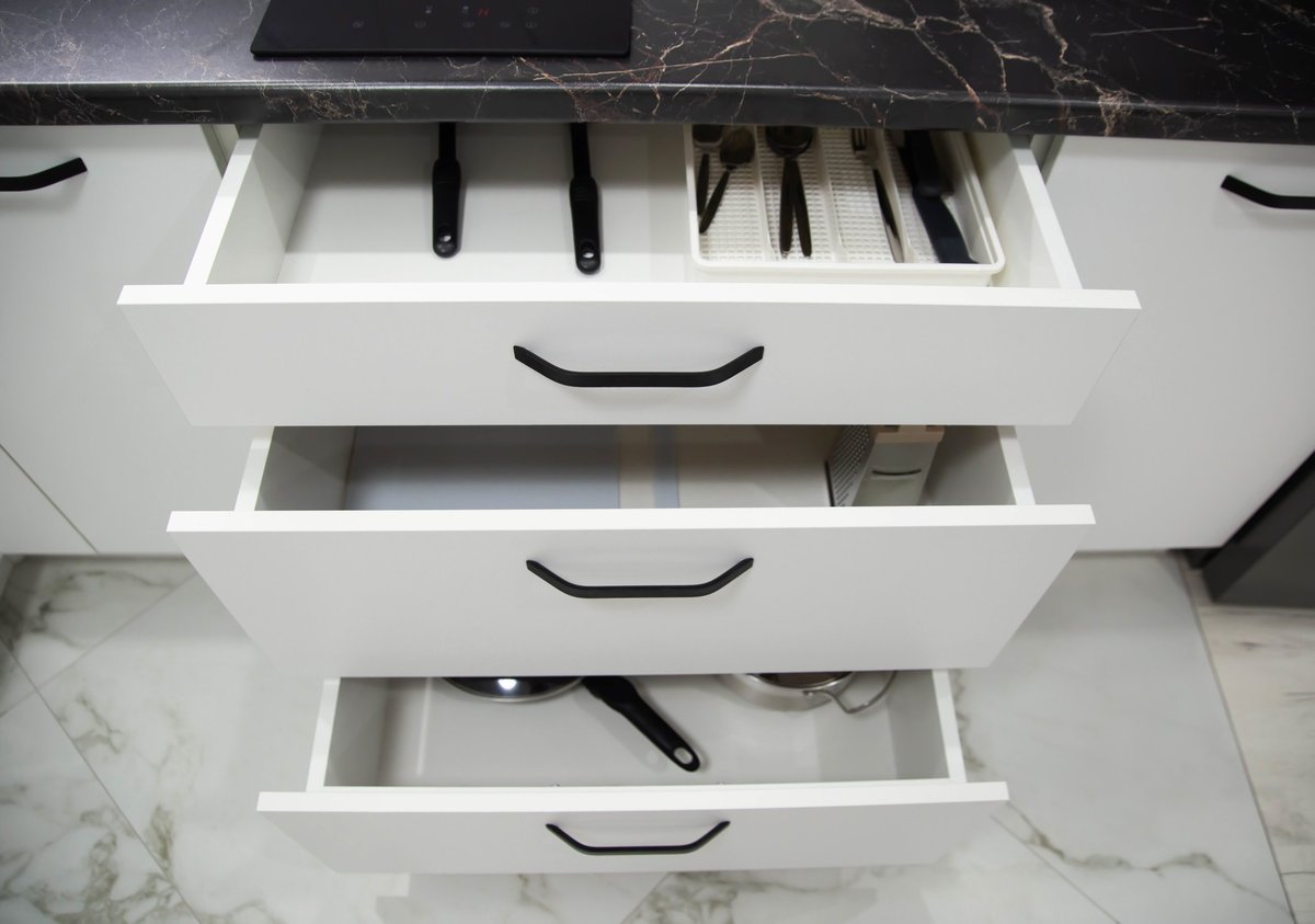 White drawers in a custom built-in kitchen. Modern fittings and furniture in the kitchen