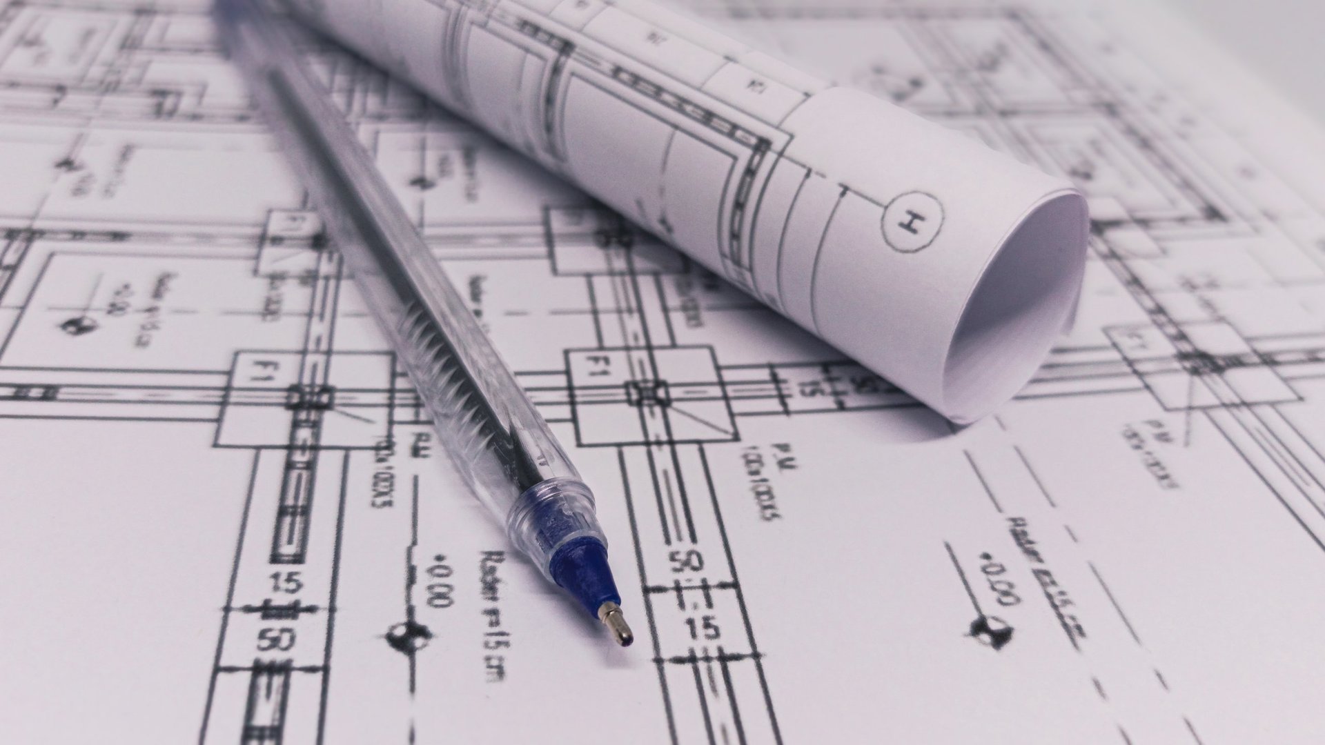 Rolled and flat blueprints with a pen, representing architecture, engineering, design review, and construction planning.