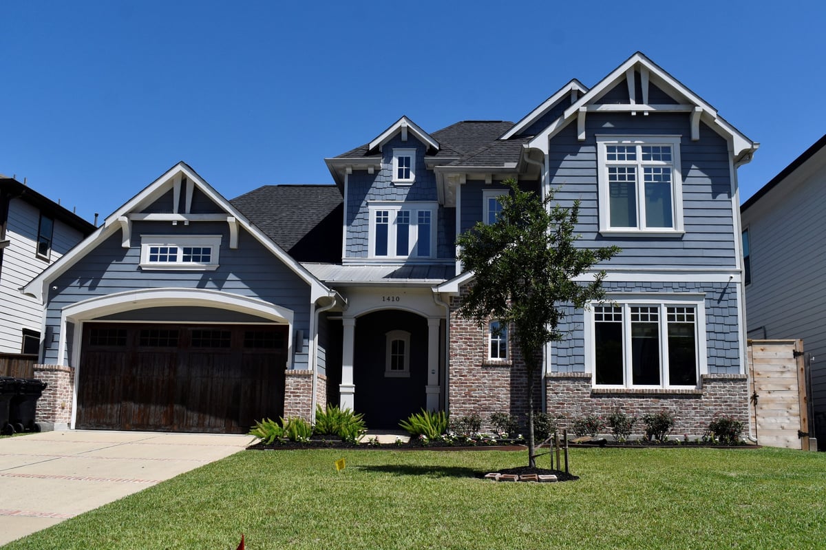 A luxurious suburban home with a light blue facade and a wooden garage door