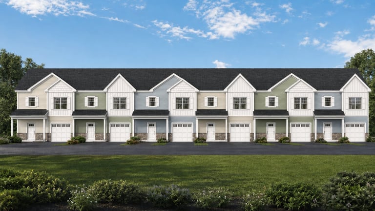 Row of identical two-story townhouses with white siding, dark roofs, and two-car garages on green lawn