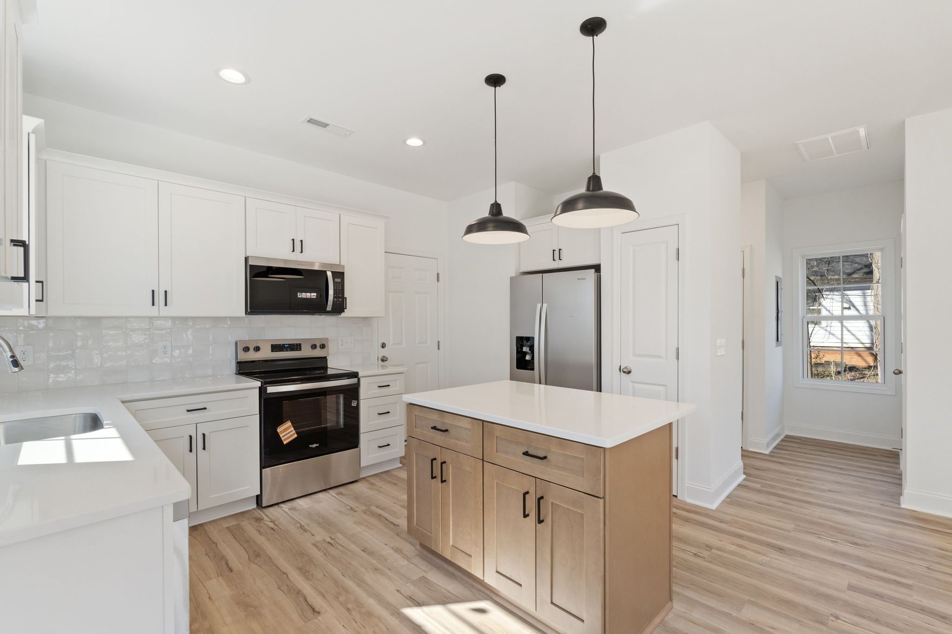 Modern kitchen with white cabinetry, wood island, stainless steel appliances, pendant lights, and hardwood flooring