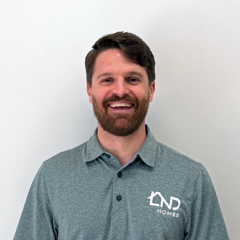 Professional headshot of a man with dark hair and beard wearing a gray polo shirt with END Homes logo
