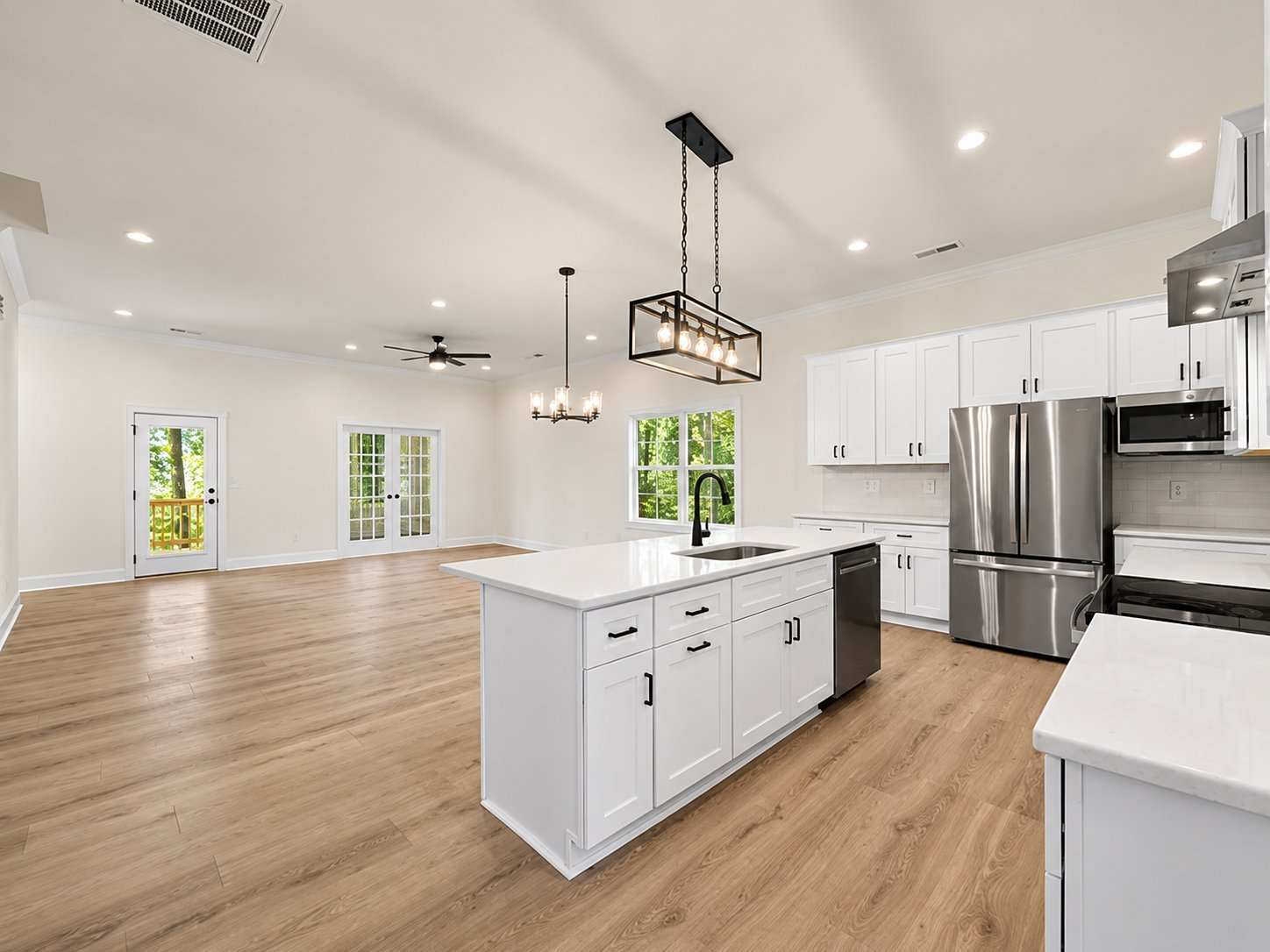 Modern kitchen with white cabinetry, stainless steel appliances, white island, wood flooring, and pendant lighting