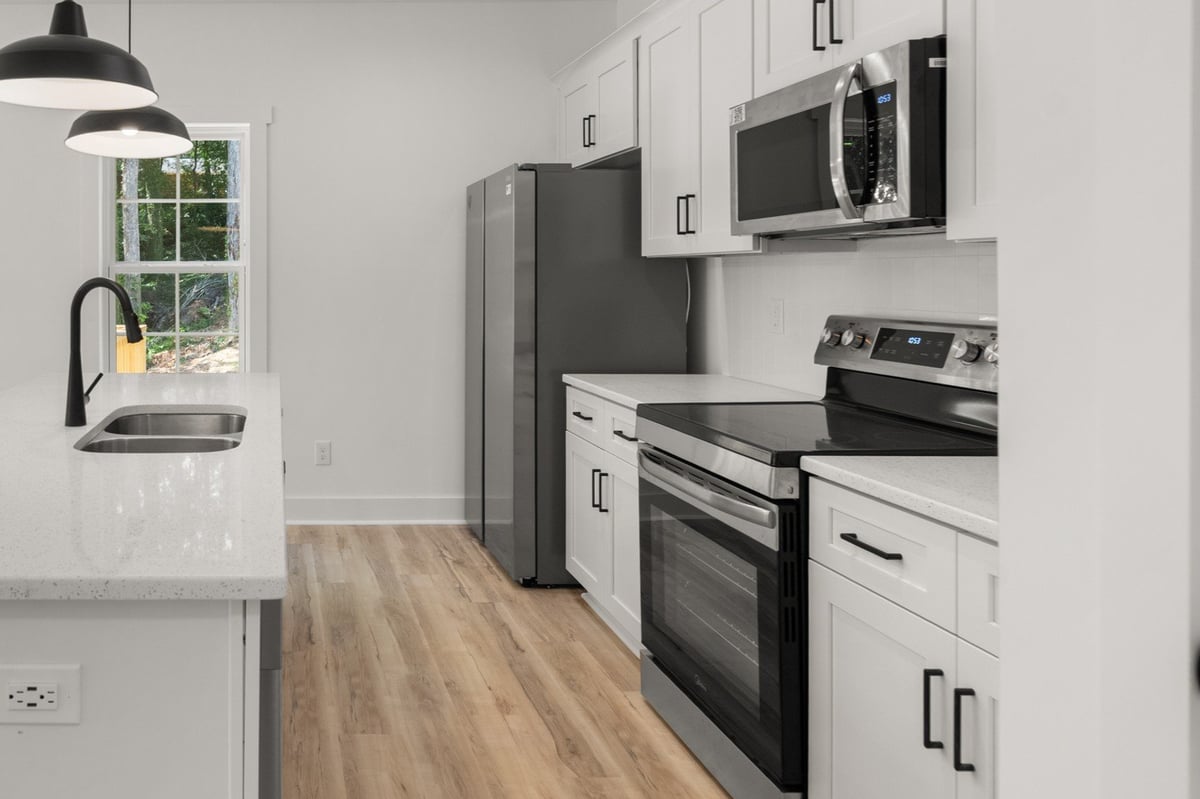 Modern kitchen with white cabinetry, stainless steel appliances, and wood flooring
