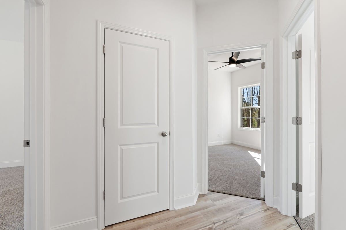 Modern hallway with white panel doors, hardwood flooring, and bright natural light from window