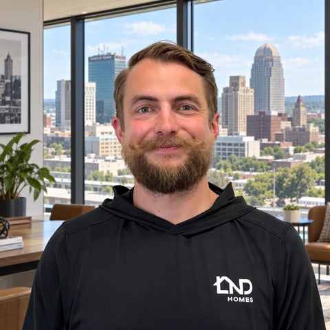 Man with beard wearing black ND Homes hoodie in office with city skyline view through windows
