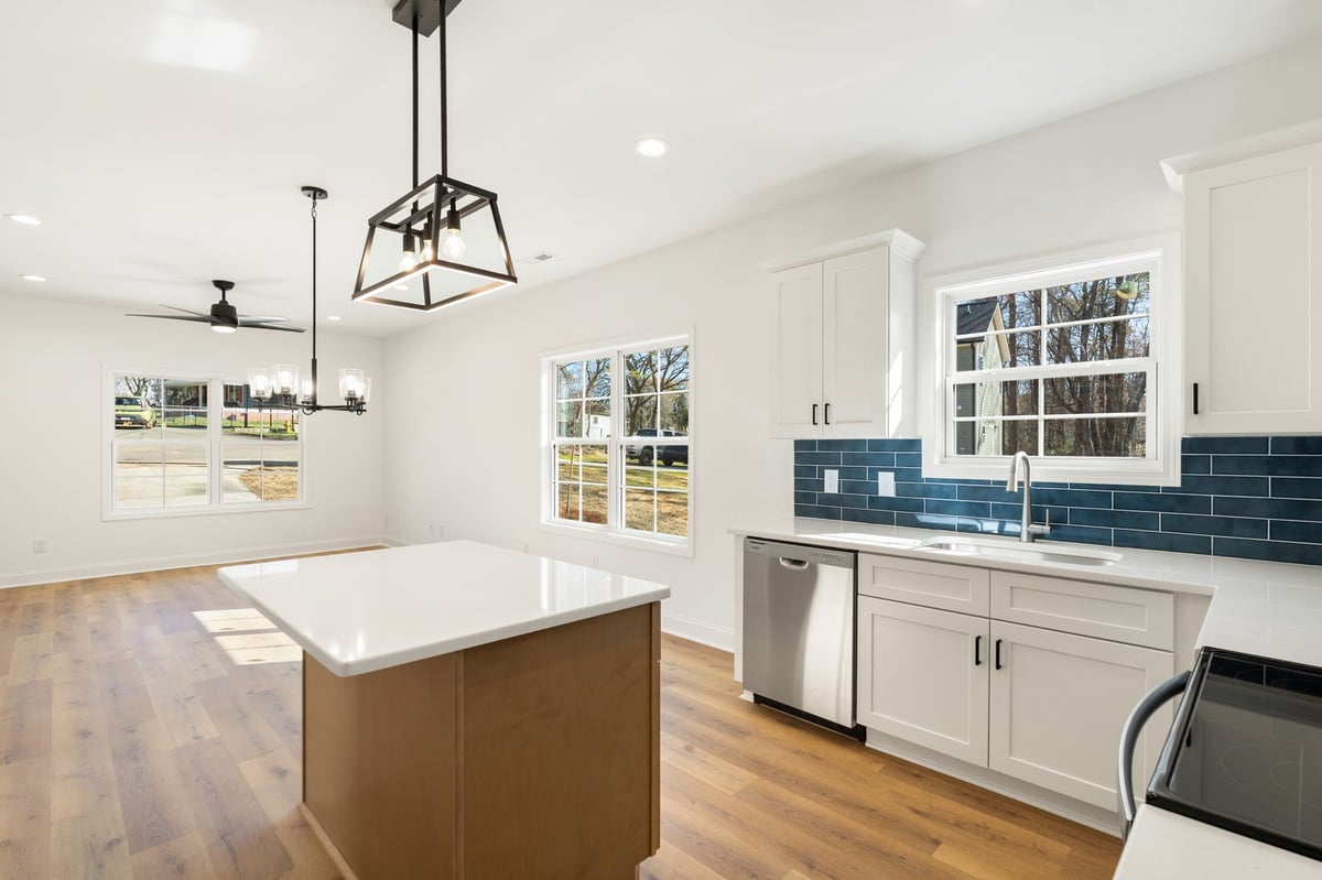 Modern kitchen with white cabinetry, brown island, blue tile backsplash, stainless steel appliances, and hardwood floors