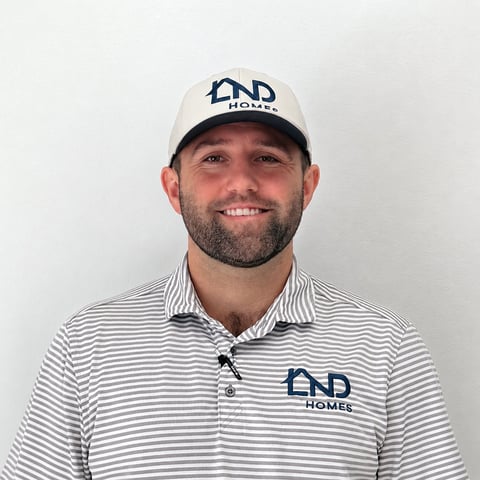 Man wearing END Homes branded cap and striped polo shirt smiling at camera for professional headshot