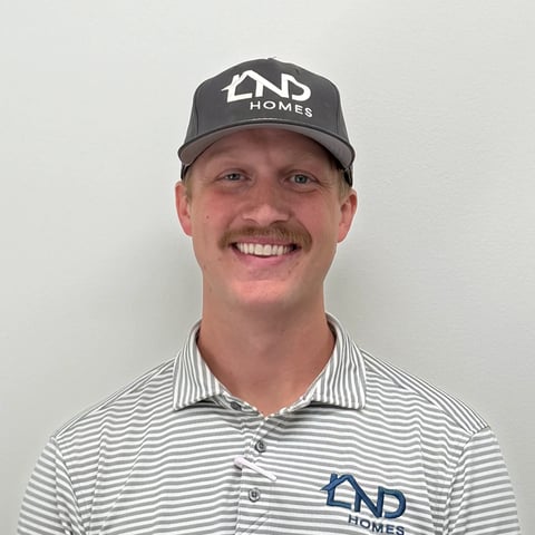 Professional headshot of a smiling man wearing a striped polo shirt and gray NP Homes cap against a white background